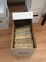 Photo showing a white cardboard storage box filled with approximately 150 comic books arranged vertically, giving an overview of the entire collection.