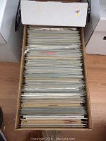 Photo of a long archive box full of comic books in sleeves, stacked vertically showing edges and thickness of comics.