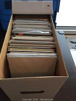 Photo showing a packed box filled with comics packed vertically in plastic sleeves.