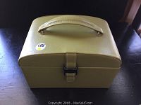 Closed view of the green faux leather jewelry box with top handle.