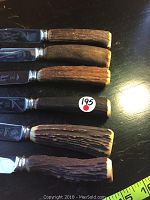 Photo showing the six steak knives laid out, highlighting the textured antler handles with natural variations and wear.