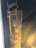 Full view of hand painted saw showing deer and birch trees on metal blade with wooden handle.