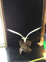 Full view of white seagull sculpture mounted on rough natural wood base with ruler display for scale.