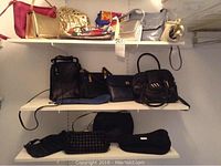 Wide view of multiple purses on three white shelves showing various styles and colors including pink, gold, black, blue, and silver purses.