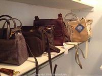 Shelf of six assorted purses in various shades of brown and tan, showing different styles and materials.