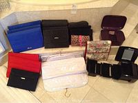 Wide shot showing multiple fabric folding jewelry organizers in various colors including black, blue, red, and floral prints arranged on floor.