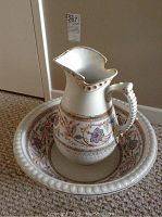 Photo of ceramic pitcher with floral and gold accents, ornate handle with ribbed texture