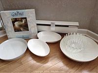 White serving lot arranged on floor including glass bowls and white ceramic pieces.