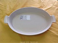 White oval ceramic dish inside, top view, showing smooth surface and sticker label inside base