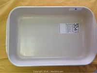 Top down photo showing the cream/beige glazed interior of the rectangular baking dish with manufacturer sticker inside the dish.