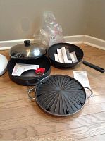 Three Circulon pans: stir fry pan, large skillet with lid, and stove top grill pan with documentation inside each.