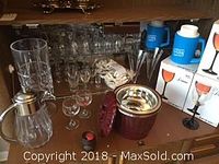 Glassware including dozen boxed Luminarc Domino wine glasses with black stems, a ribbed clear glass pitcher with metal cap, and vintage red glass ice tub with metallic rim and lid handle