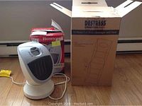 Photo showing the Destress full body massager's original box alongside the Honeywell heater in front of its box.