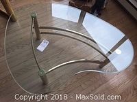Top down view of the boomerang-shaped glass tabletop on brass base showing small chip on glass.
