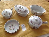 Five-piece Birks French porcelain set with 'Birds of Paradise' floral and bird decoration, showing all items on a yellow surface.
