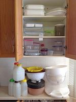 Multiple shelves and cabinets filled with assorted plastic kitchen containers and bowls, showing a variety of sizes and colors.