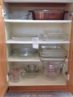 Photo showing several glass bakeware dishes on upper and middle shelves, including round and rectangular baking dishes and plates.