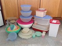 Wide view showing most of the Tupperware containers in the lot including bowls, lids, cups, and boxes.