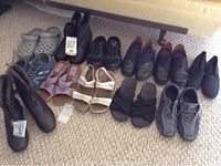 Full view of all assorted shoes and boots including clogs, sandals, sneakers, and boots arranged on carpet