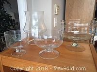 Four clear glass trifle dishes of various sizes on a wooden surface, showing the front and side views.