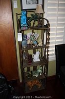 Full view of four-tier folding metal shelving unit holding various decorative items, showing palm tree design backs and overall structure.