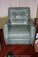 Front view of the green leather recliner arm chair showing cushioned tufted back and seat with padded armrests.