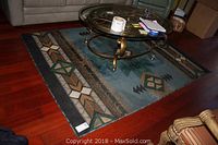 Full photo showing the rug under a coffee table, illustrating its color, size, and placement in a room.