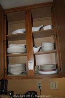 Image showing Mikasa white dinnerware in cabinet including plates, bowls, fish-shaped soup bowls, and a teapot all with hand painted floral details