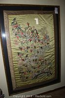 Frontal view of fully framed silk tapestry showing intricate embroidered figures and overall condition including a small white spot marked on the glass.