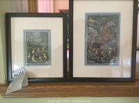 Front view showing both framed Balinese etchings side by side on a wooden surface; black simple frames and cream-colored mats with blue inner border showing detailed artwork inside; lot tag visible