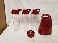 Photo showing Robert Irvine red personal blender base and three clear blending bottles with red lids, one lid separated.