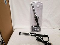 Two Conair curling irons shown, one packaged and one loose, with visible power cords and clamps.
