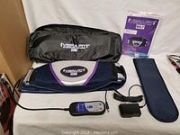 Full set of Vibrafit vibration belt with carry case, wired controller, measuring tape, and manual on a white surface.