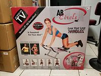 Photo of AB Circle Pro box showing exercise equipment and female model demonstrating use.