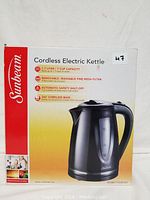 Photo shows the front of the Sunbeam electric kettle box displaying the kettle image and features like 1.7 L capacity, removable filter, safety shut-off, and cordless base.