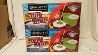 Two Gravitti Spin Mop boxes stacked, showing branding and product image of spin mop bucket with white basket