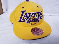 Front view of new yellow Los Angeles Lakers hat with embroidered logo and Mitchell & Ness sticker on brim.