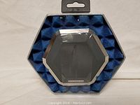 Hexagonal Boombotix Bluetooth speaker with metal grill inside protective blue foam packaging in a hexagonal box.