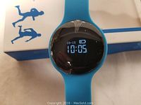 Photo of smart bracelet showing digital time display on the round screen with blue silicone band.