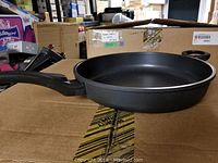 Side view of the black Starbasix heavy duty fry pan showing the long handle and overall shape.