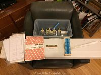 Full overview of machine head on chair with instruction book, punch cards, Handy Punch box, ruler and plastic bin with small tools