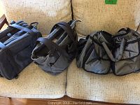 Three gray and black diaper bags, slightly different designs and sizes, displayed on a beige couch.