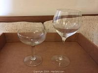 Two different types of stemmed glasses shown: a shorter coupe style glass and a tall wine glass with large bowl.