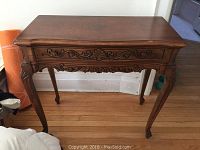 Full front view of carved wooden desk table showing overall shape and carved details