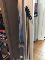 Full view of Karhu Pioneer skis and Swix poles leaning against wall on wooden floor