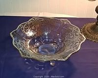 Clear glass footed bowl with sterling silver overlay, showing ornate Urn and Vine pattern and thick silver rim.