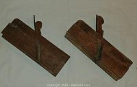 Two antique wooden hand planes placed side by side, showing top and side profile, with metal lever caps, wooden handles, and adjustment screws visible.