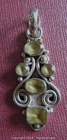 Front view of the sterling silver pendant displaying four bezel set citrine quartz stones with various shapes including oval and rectangular, set amidst silver swirls and bead accents.
