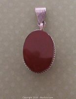 Front view of oval carnelian stone set in bezel silver pendant with tribal detailing visible on the pendant sides and bail.