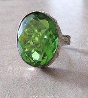 Close-up image showing the vibrant green facetted quartz stone set in a sterling silver ring with a decorative bezel.